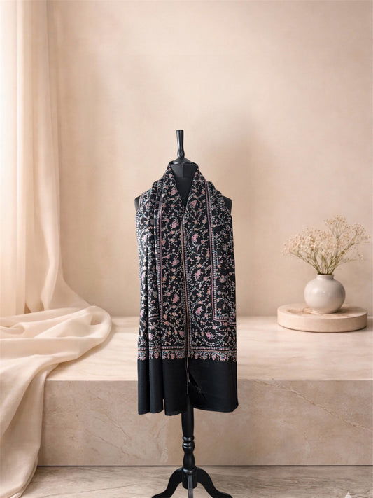 Black pashmina shawl with multicolour floral embroidery worn over the shoulders, front view