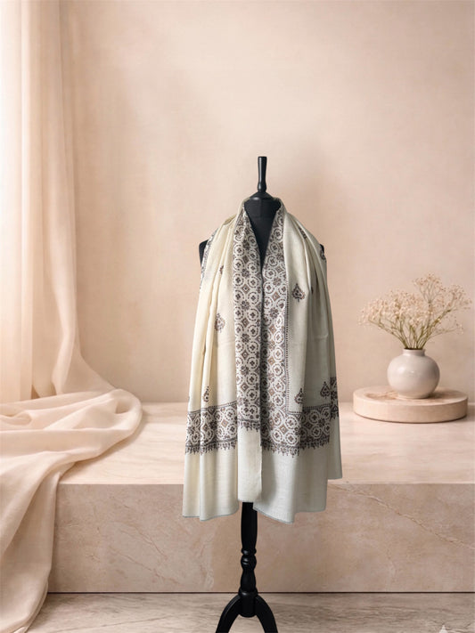 Ivory pashmina shawl with black embroidered border worn over the shoulders, front view