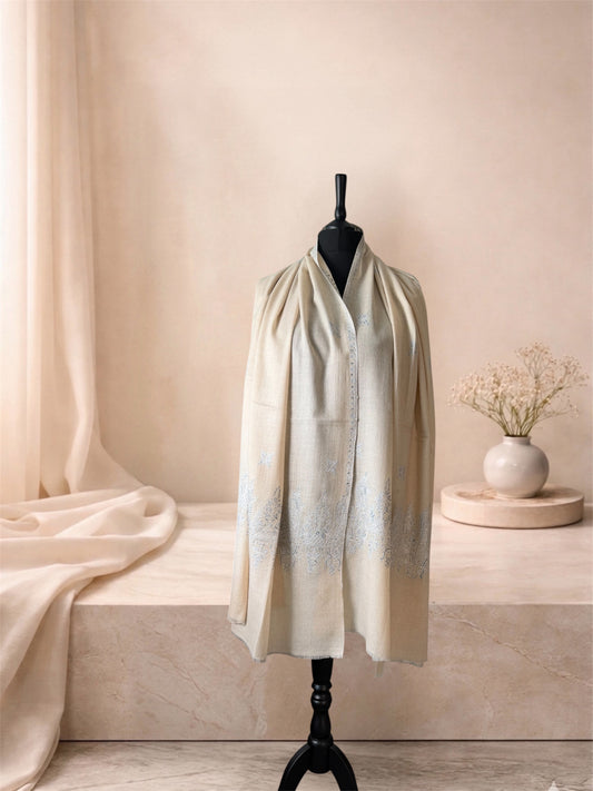 Cream pashmina shawl with pale blue Sozni embroidery worn over the shoulders, front view