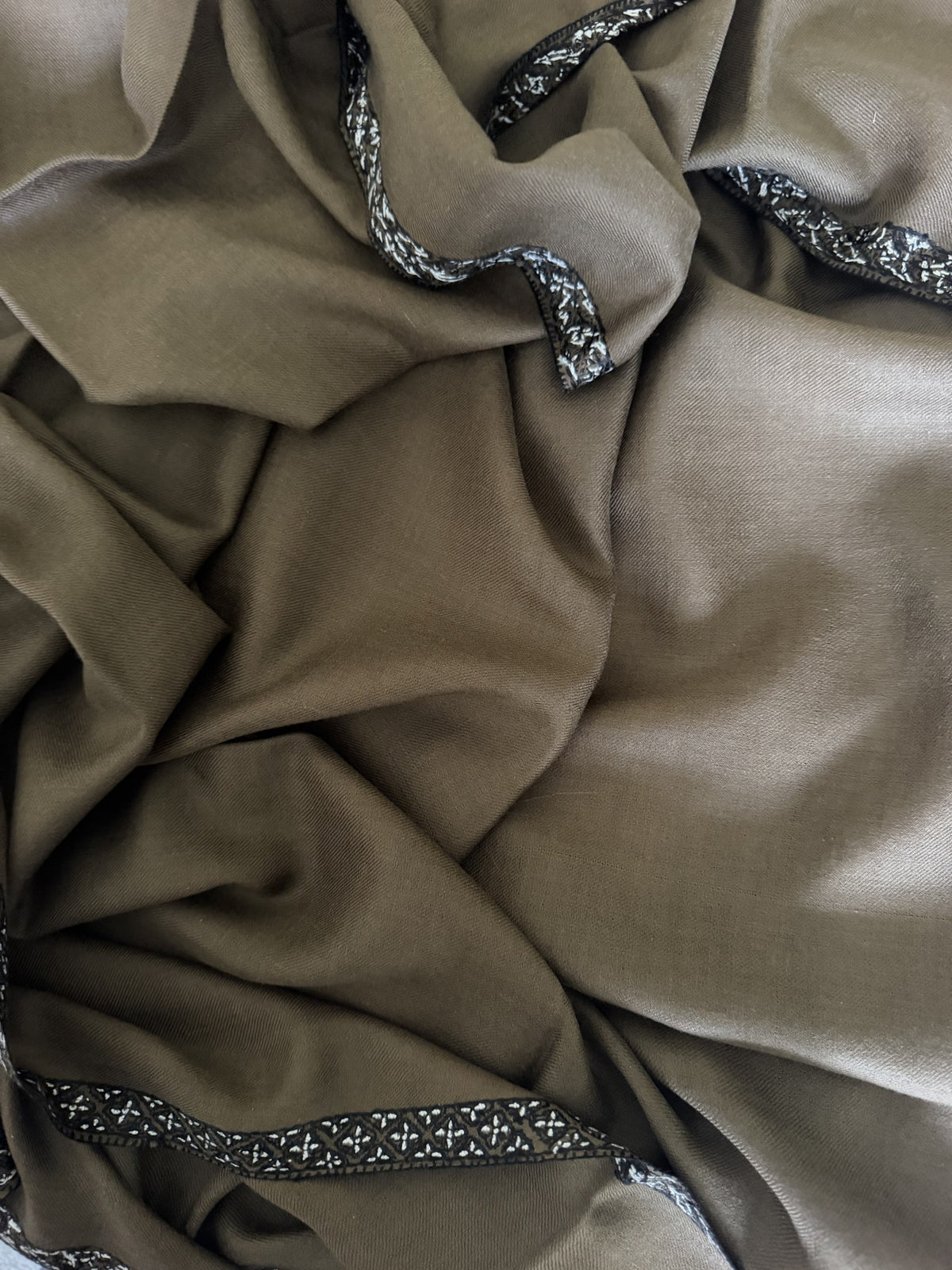 Close-up of black and white Sozni border on camel brown pashmina