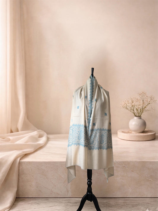 Ivory pashmina shawl with blue Sozni end bands worn over the shoulders, front view