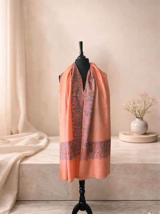 Peach pashmina shawl with paisley border worn over the shoulders, front view