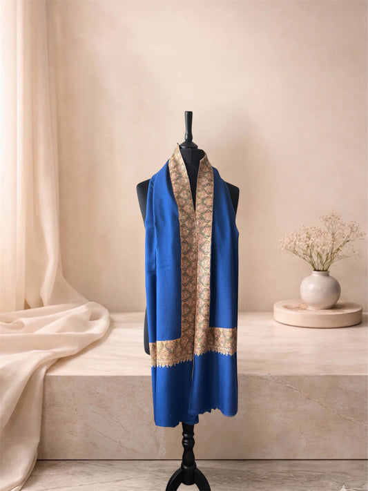 Royal blue pashmina shawl with gold paisley border worn over the shoulders, front view