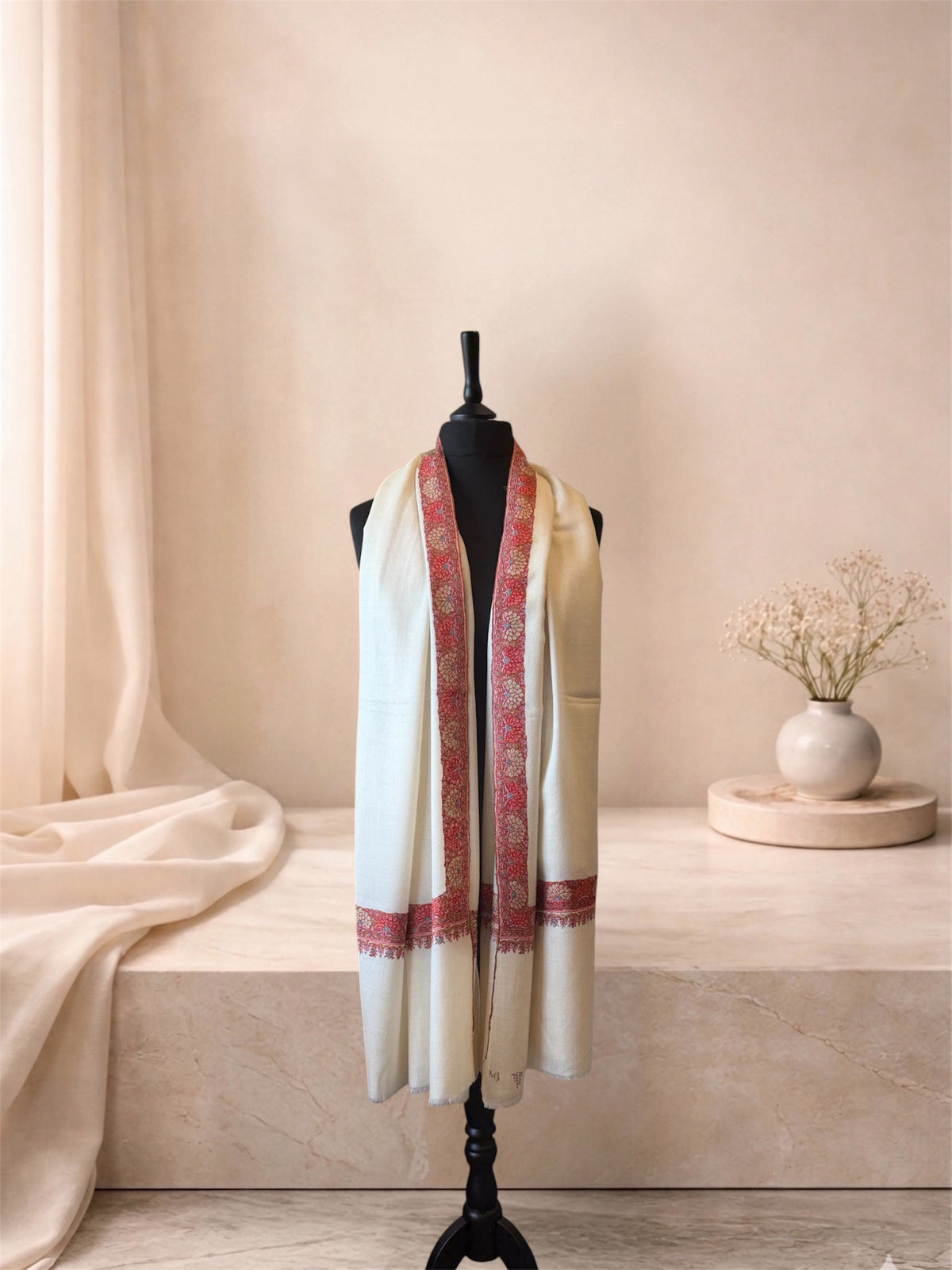 Ivory pashmina shawl with coral daisy border worn over the shoulders, front view