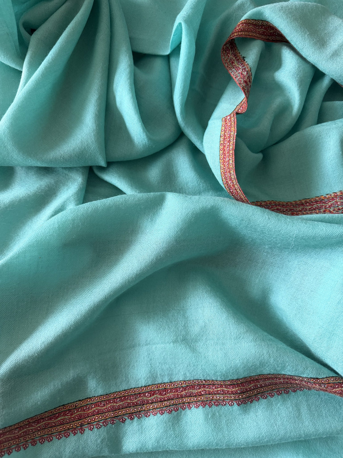 Close-up of rust red Sozni leaf border on aqua mint pashmina