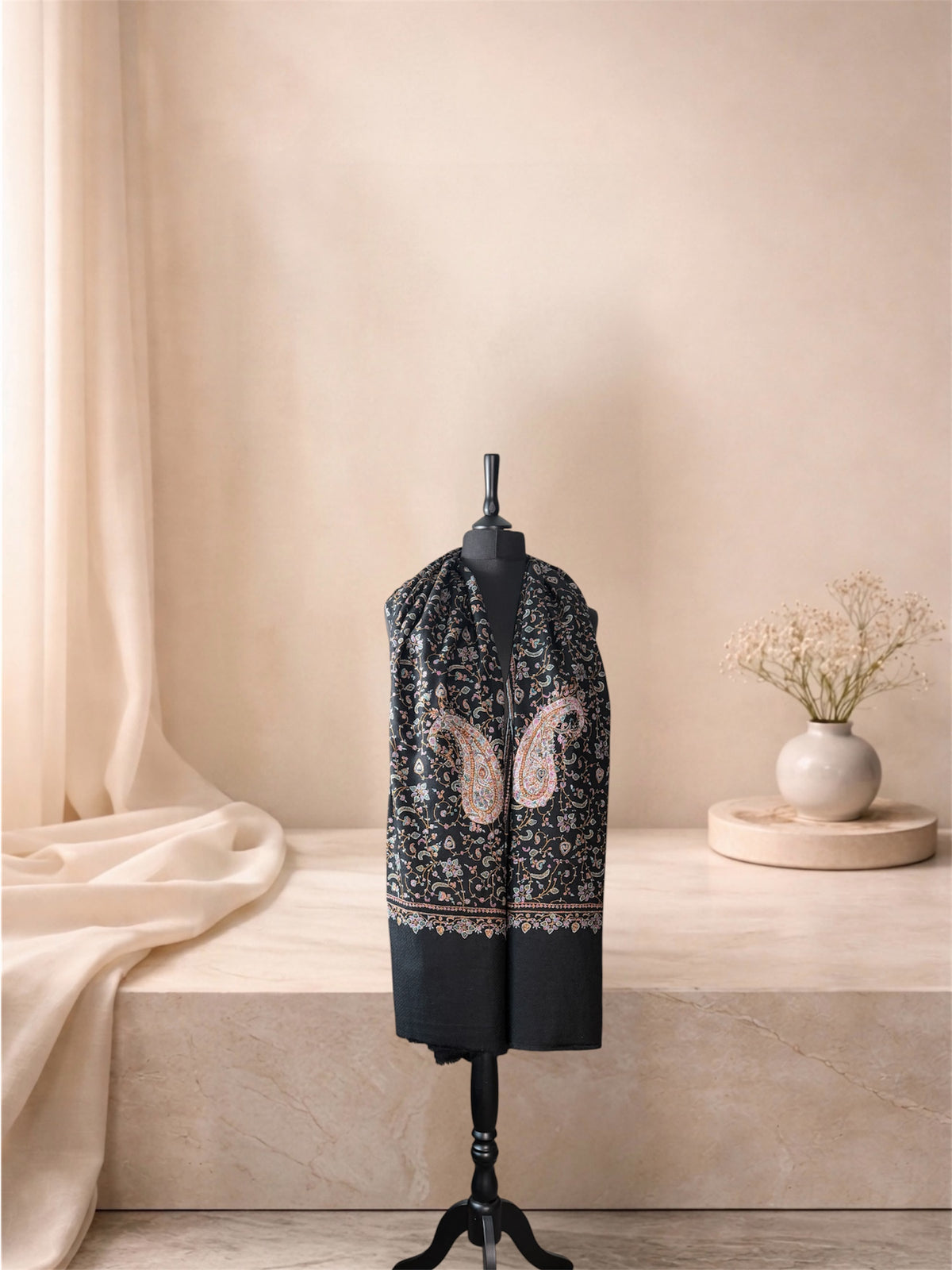 Black pashmina shawl with large embroidered paisleys worn over the shoulders, front view