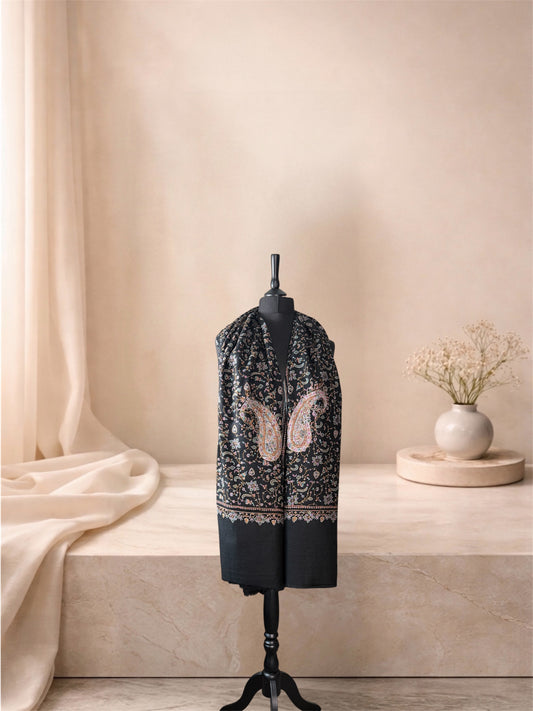 Black pashmina shawl with large embroidered paisleys worn over the shoulders, front view