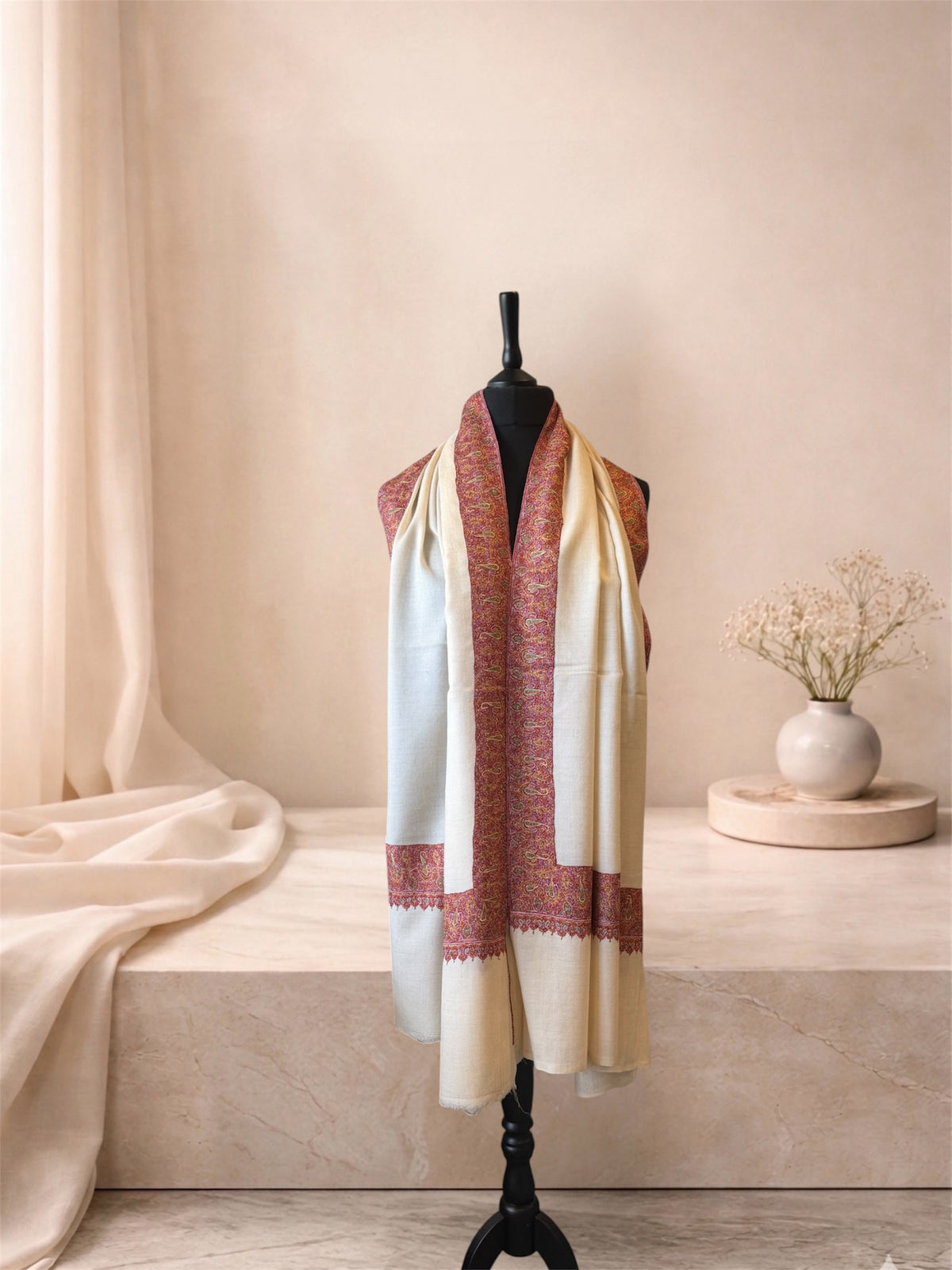 Ivory pashmina shawl with red and gold border worn over the shoulders, front view