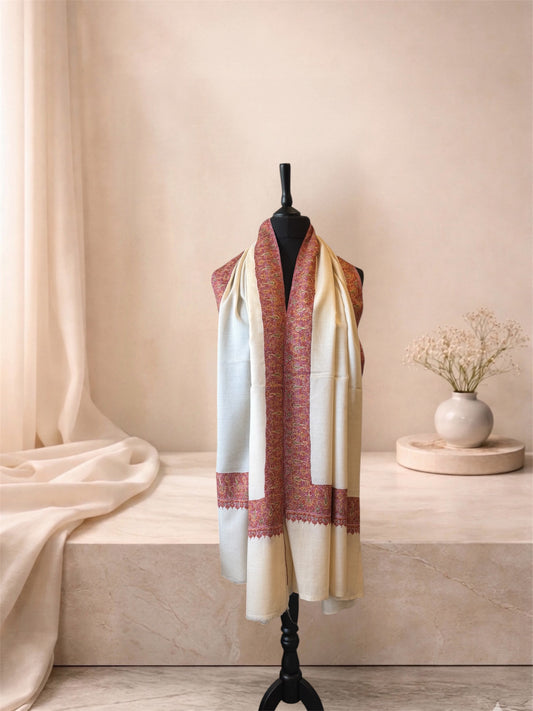 Ivory pashmina shawl with red and gold border worn over the shoulders, front view