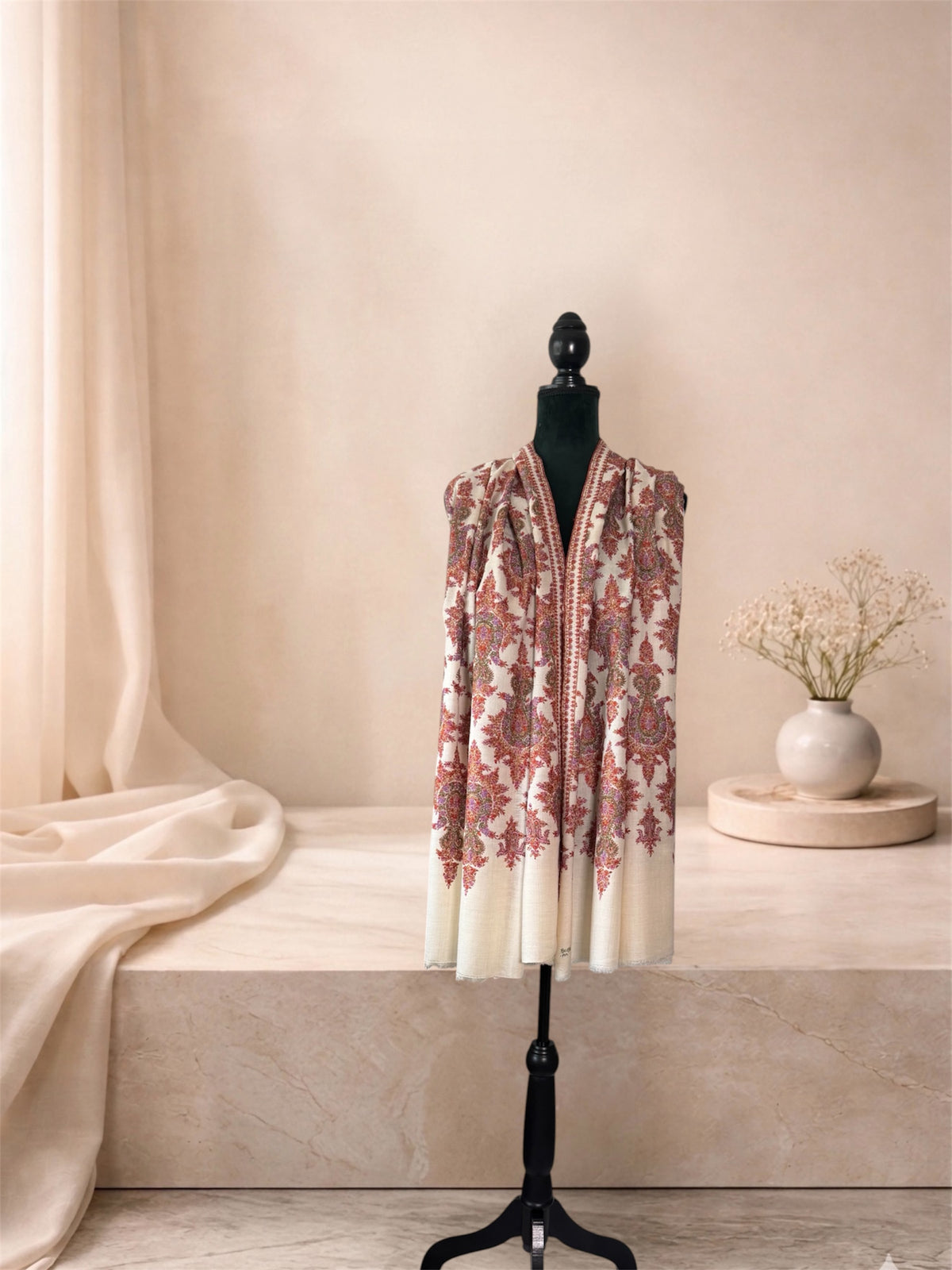 Ivory pashmina shawl with rust red paisley embroidery worn over the shoulders, front view