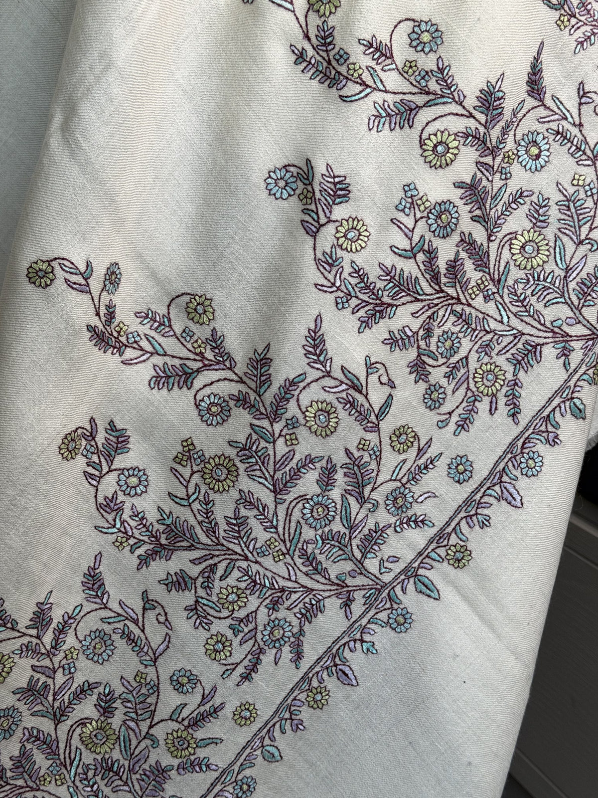 Close-up of plum and lilac Sozni flowering vines on ivory pashmina