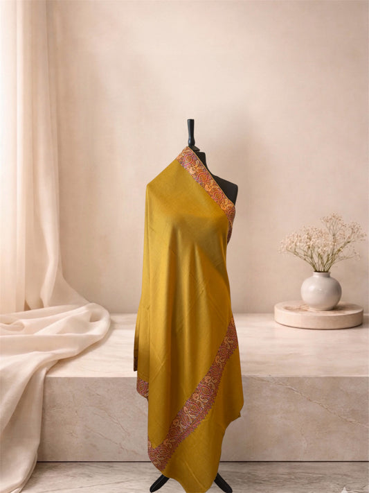 Mustard pashmina shawl with pink Sozni paisley border draped on a mannequin, side view