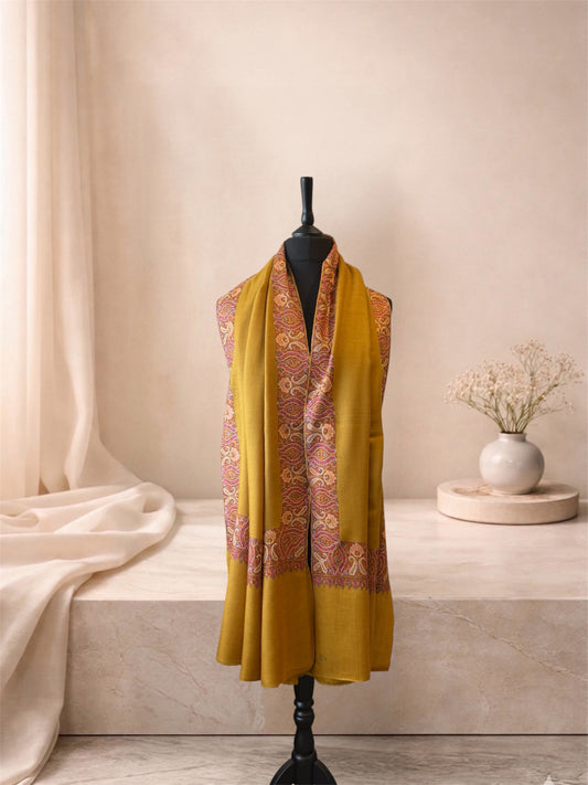 Mustard pashmina shawl with paisley border worn over the shoulders, front view