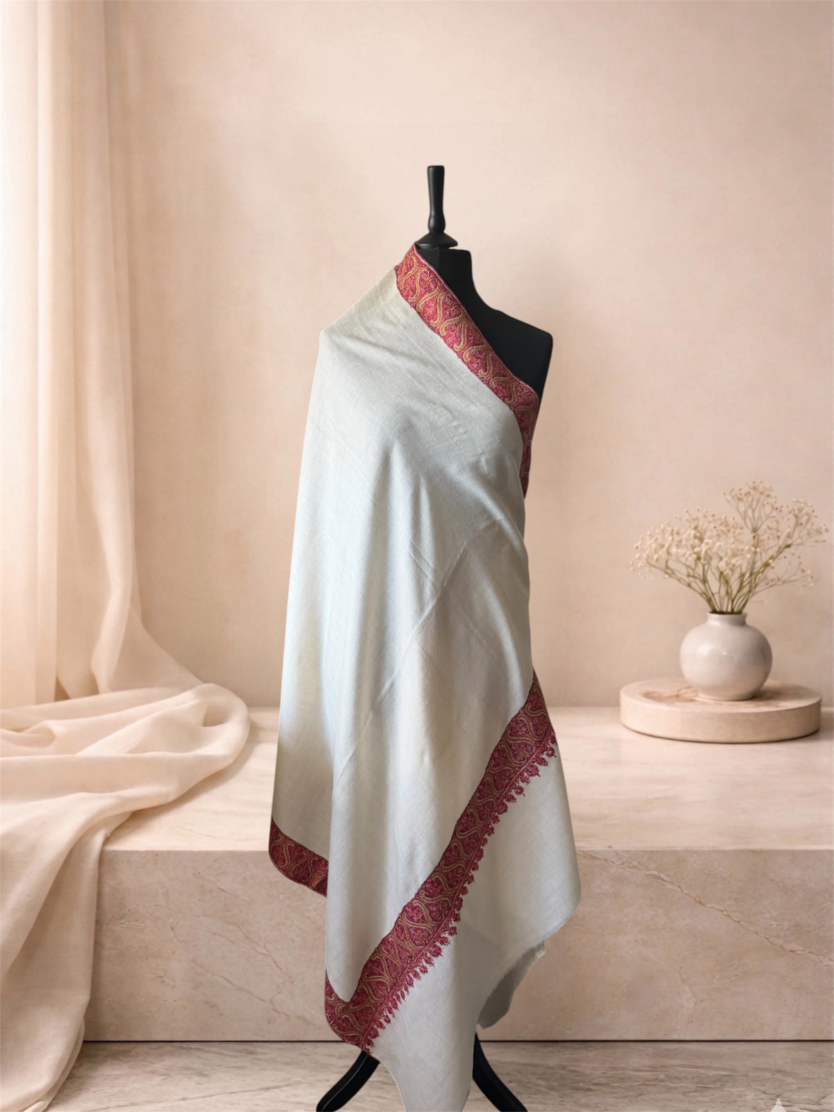 Ivory pashmina shawl with crimson Sozni paisley border draped on a mannequin, side view