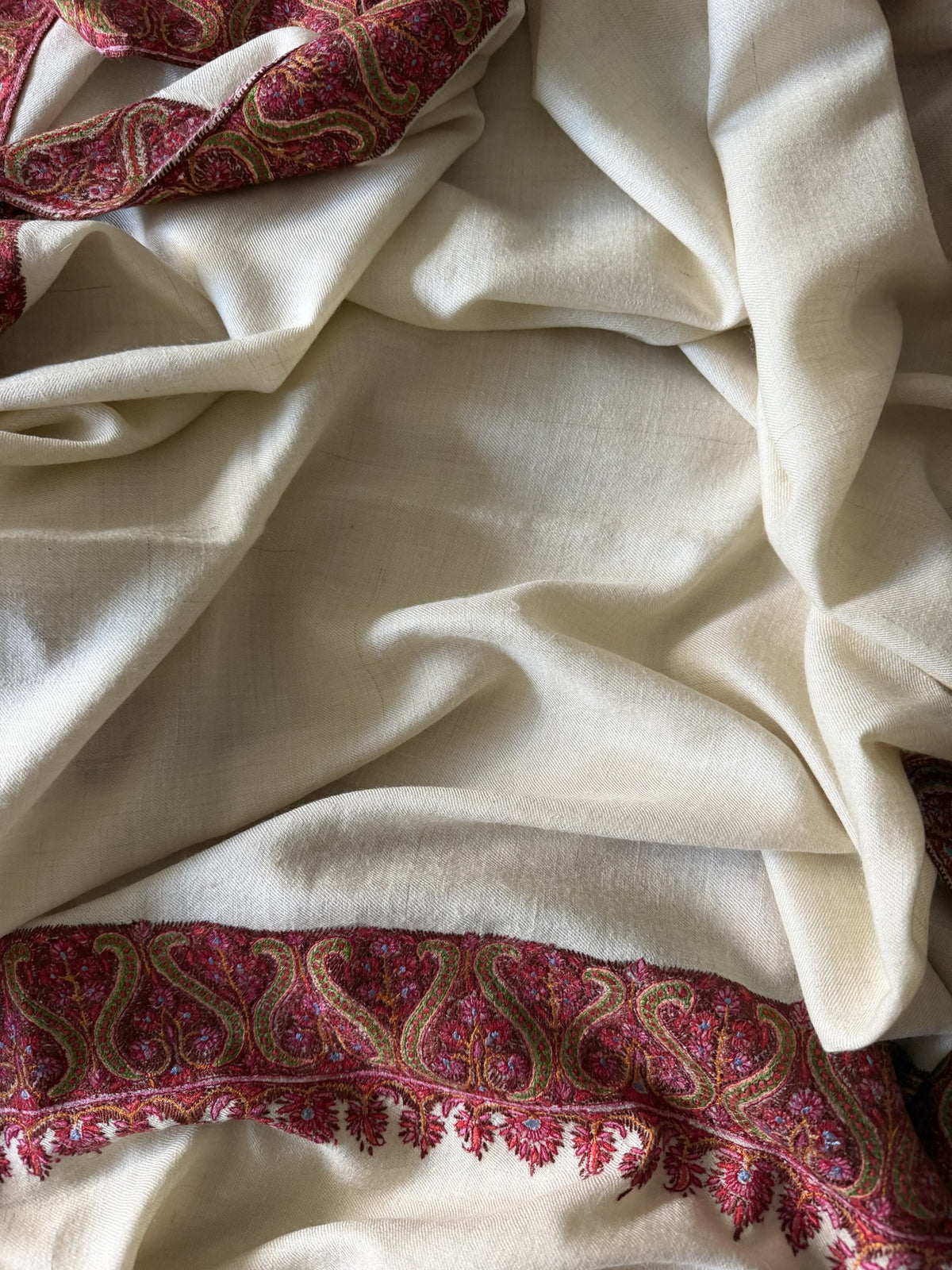 Close-up of crimson and magenta Sozni paisley border on ivory pashmina