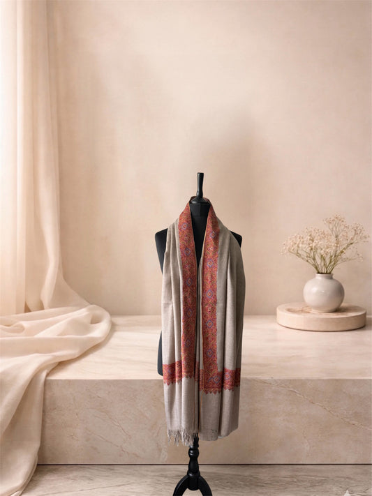 Natural beige pashmina shawl with red embroidered border worn over the shoulders, front view