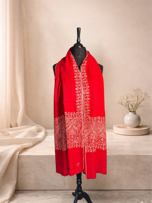 Red pashmina shawl with pale embroidered end panels worn over the shoulders, front view