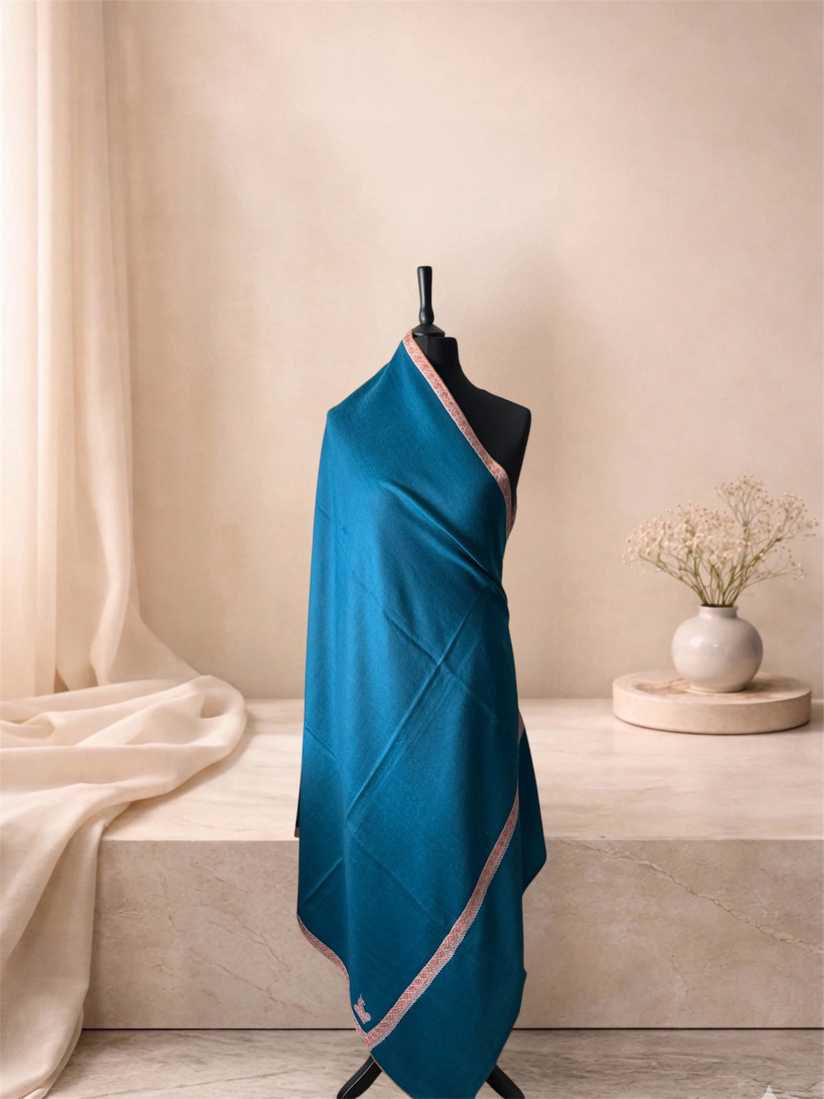 Teal blue pashmina shawl with coral border draped on a mannequin, side view