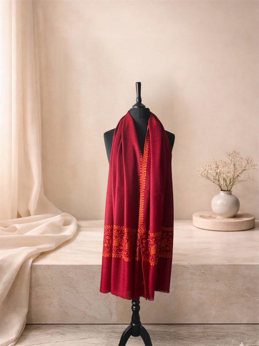 Crimson red pashmina shawl with orange paisley end bands worn over the shoulders, front view