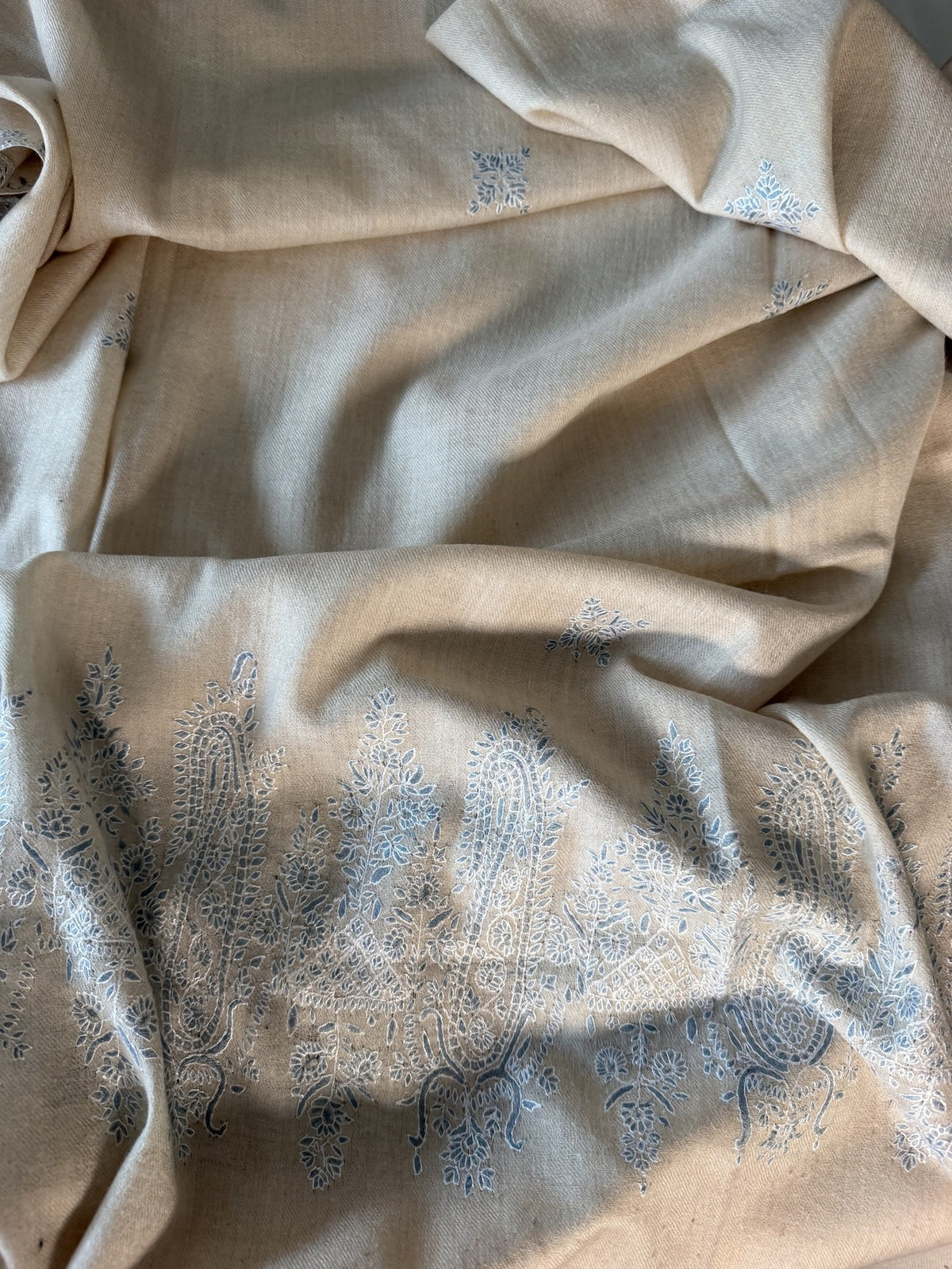 Close-up of powder blue and ivory Sozni paisleys and butis on cream pashmina