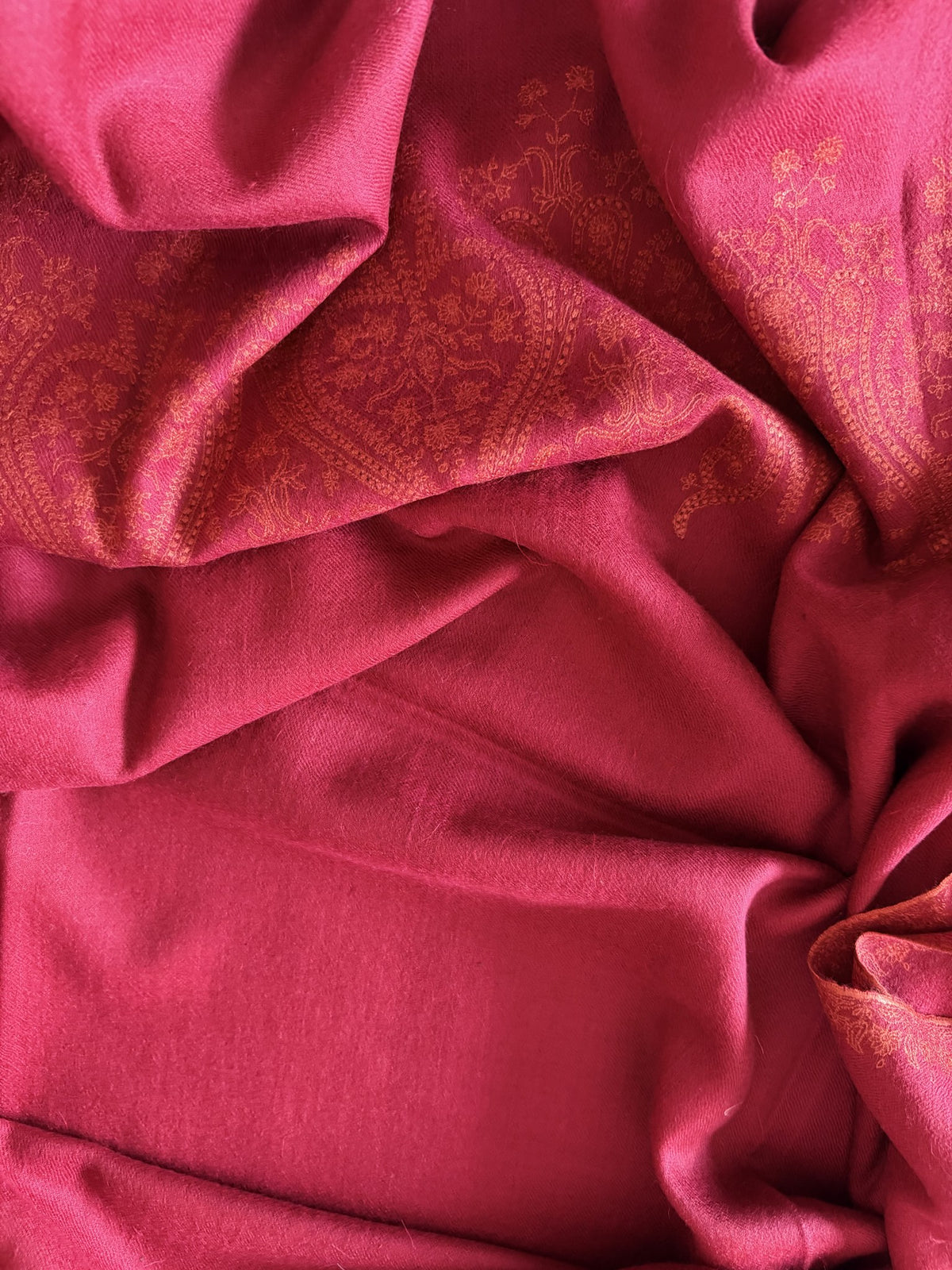 Close-up of tonal coral Sozni paisley embroidery on raspberry red pashmina