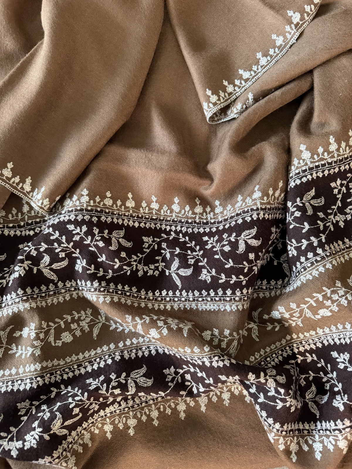 Close-up of ivory Sozni vines on chocolate bands of camel pashmina