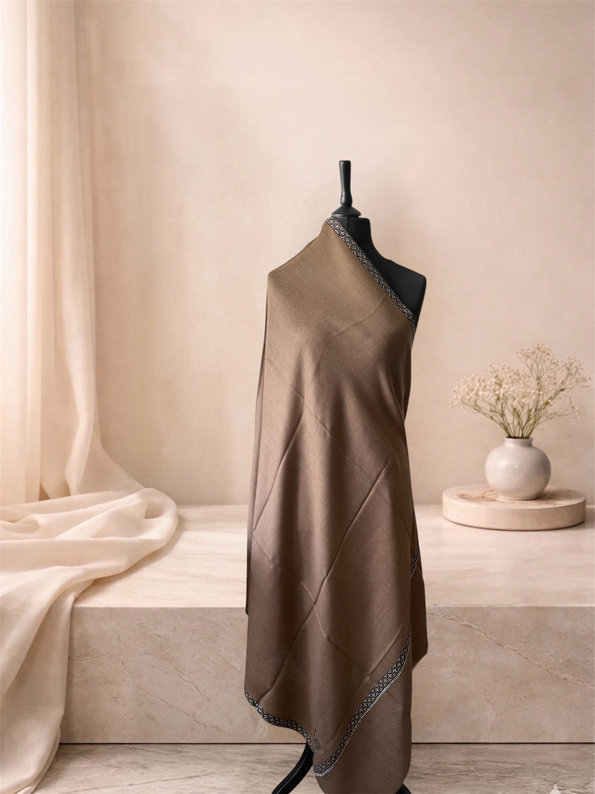 Camel brown pashmina shawl with narrow black and white border draped on a mannequin, side view