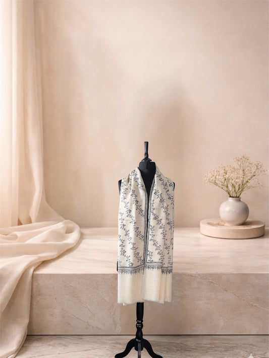 Ivory pashmina shawl with charcoal floral embroidery worn over the shoulders, front view