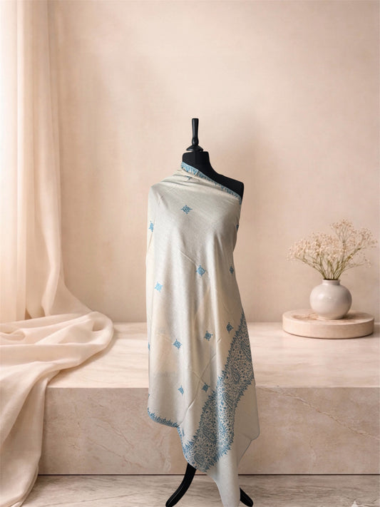 Ivory pashmina shawl with denim blue paisley border draped on a mannequin, side view