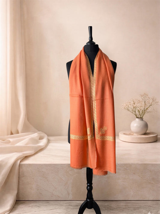 Burnt orange pashmina shawl with gold Sozni border worn over the shoulders, front view
