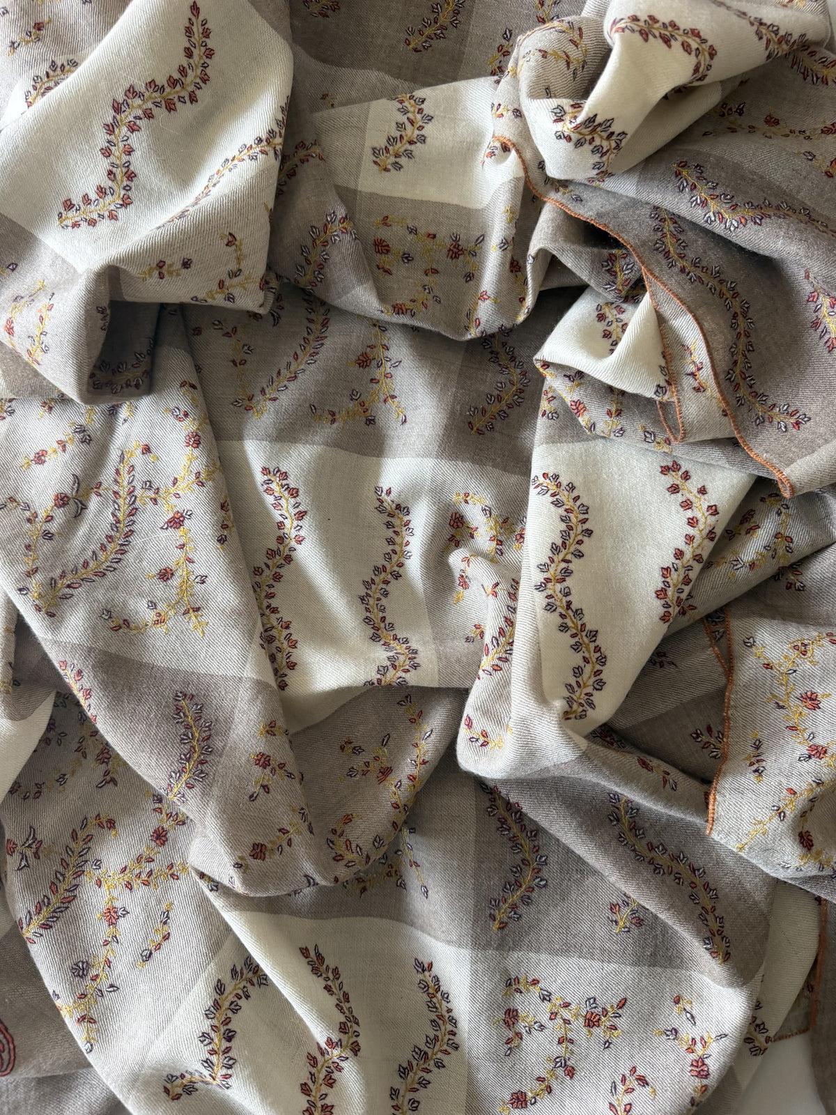 Close-up of russet and gold Sozni sprigs on taupe and ivory checked pashmina