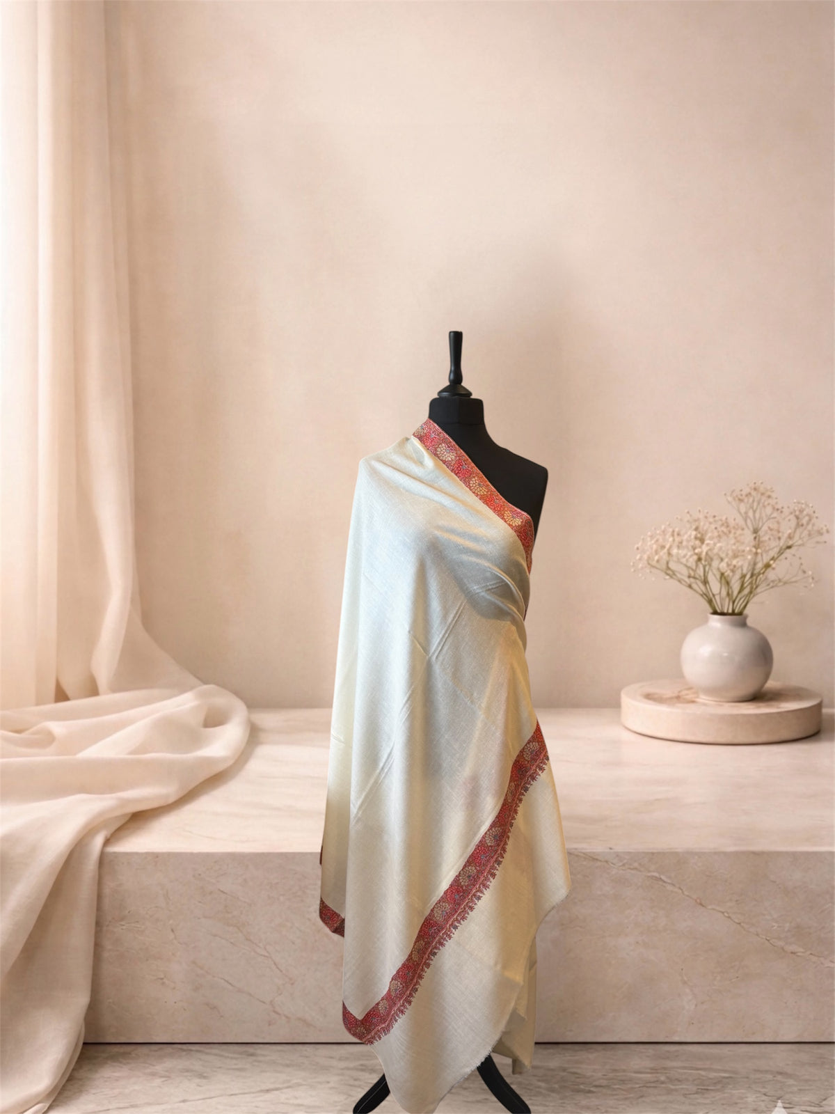 Ivory pashmina shawl with coral red floral border draped on a mannequin, side view