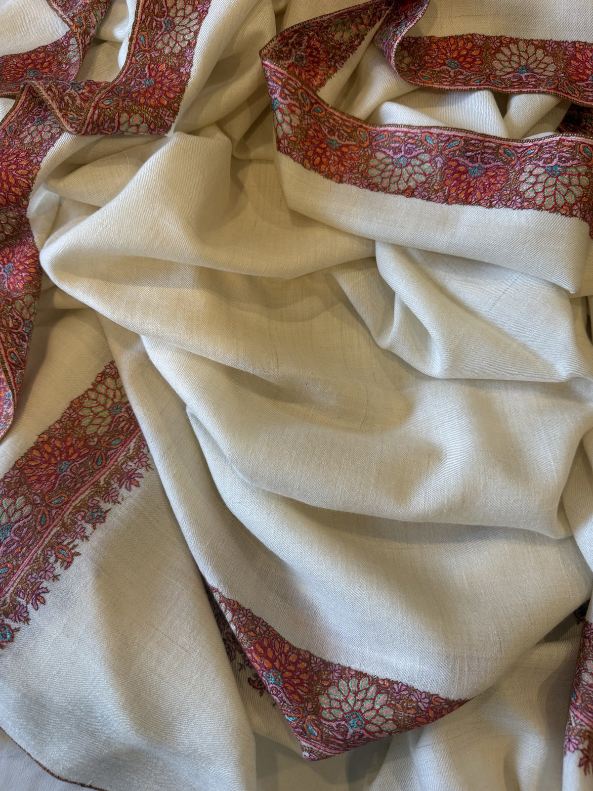 Close-up of coral red Sozni border with pale blue daisies on ivory pashmina