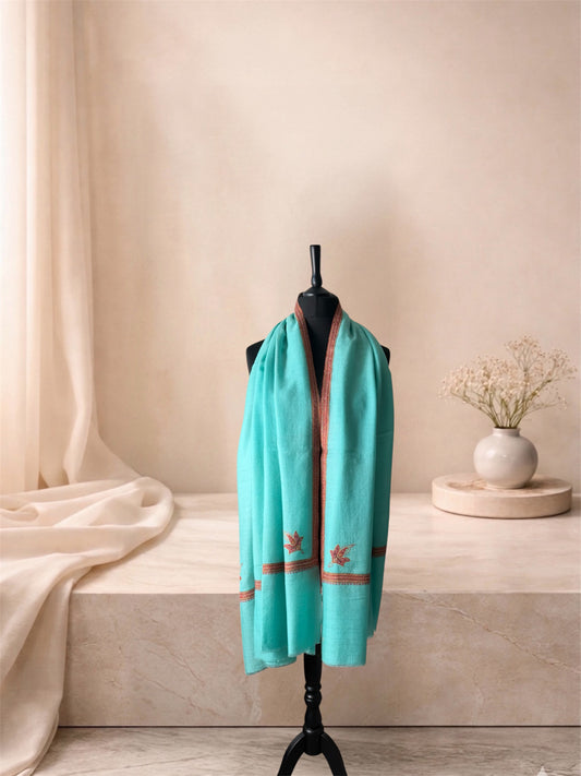 Aqua mint pashmina shawl with rust leaf motifs worn over the shoulders, front view