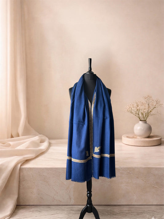 Denim blue pashmina shawl with gold Sozni border and leaf motif worn over the shoulders, front view