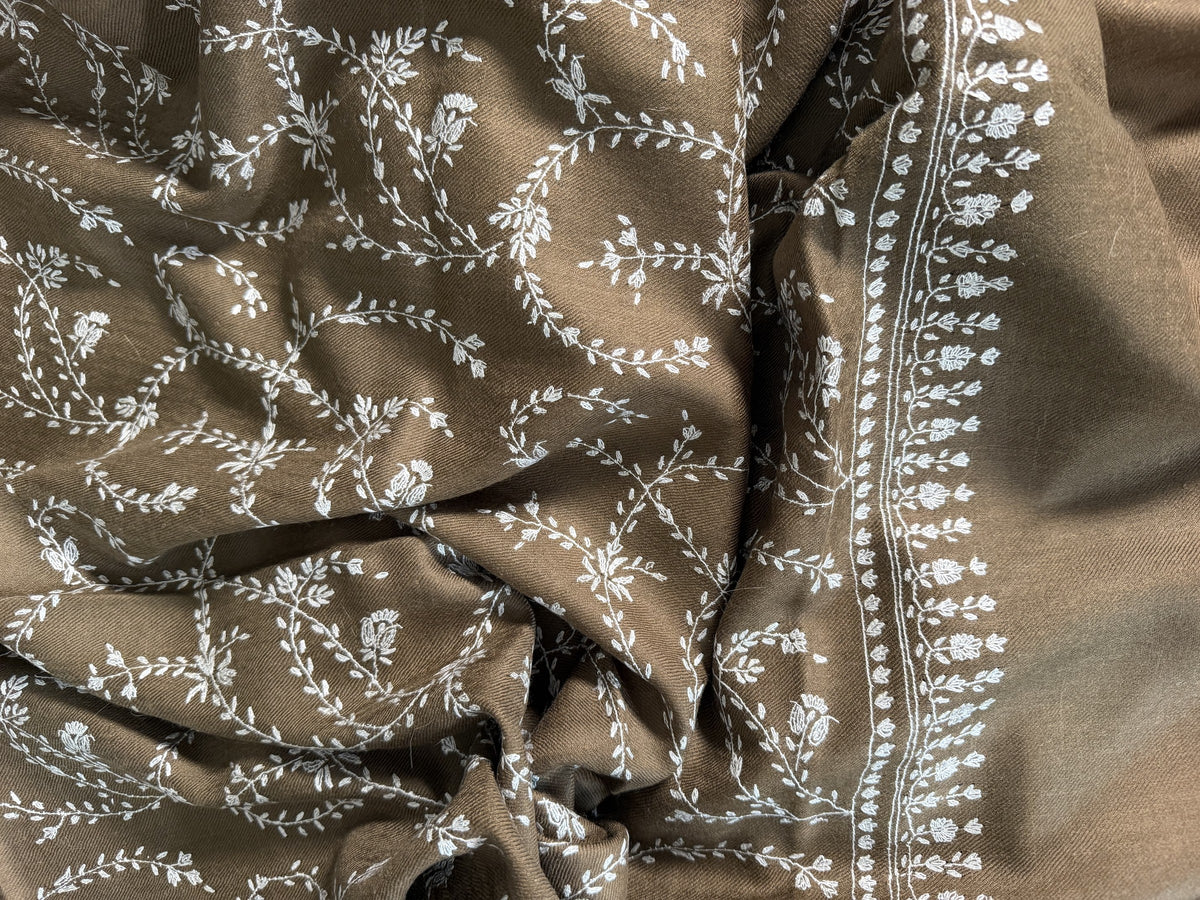 Close-up of ivory Sozni trailing vines and flower sprig border on olive brown pashmina