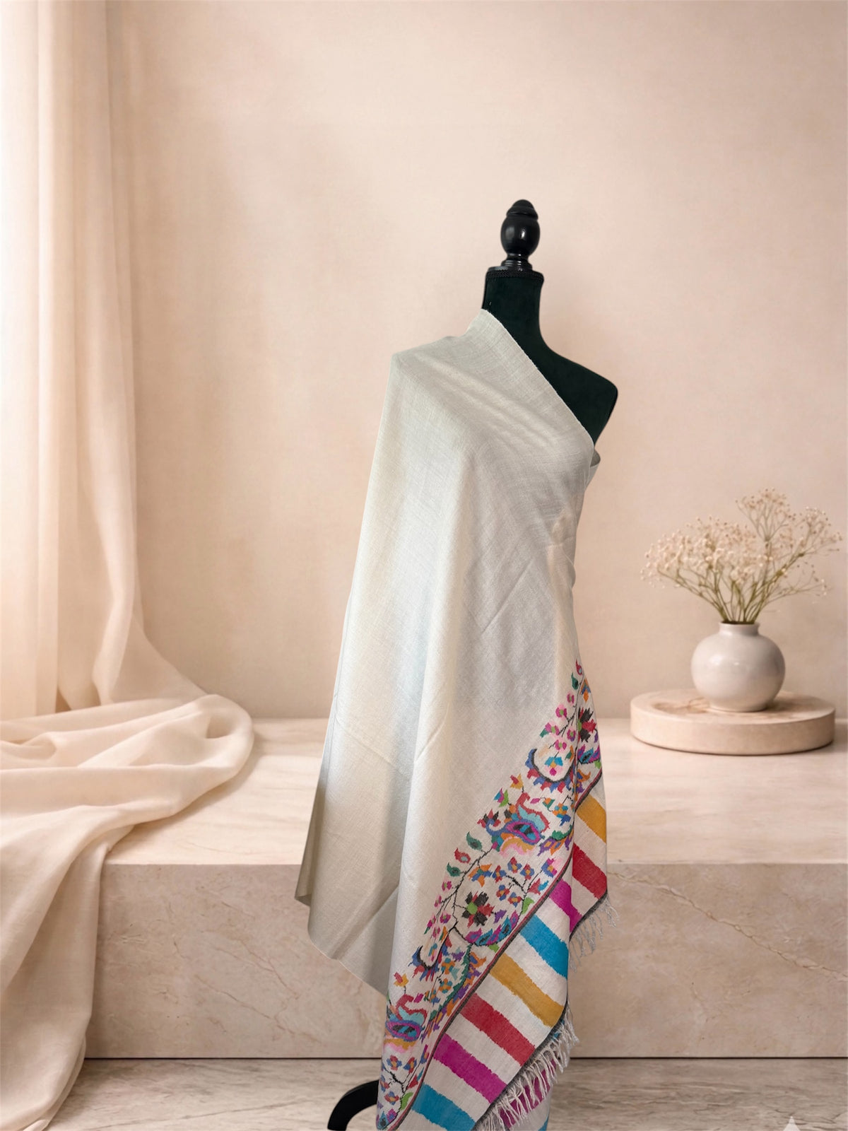 Ivory Kani pashmina shawl with multicolour striped ends draped on a mannequin, side view