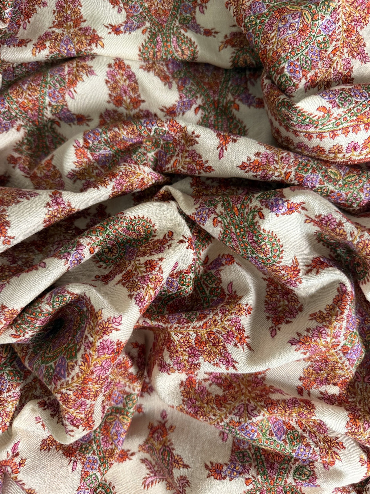 Close-up of rust red, rose and lilac Sozni paisleys on ivory pashmina