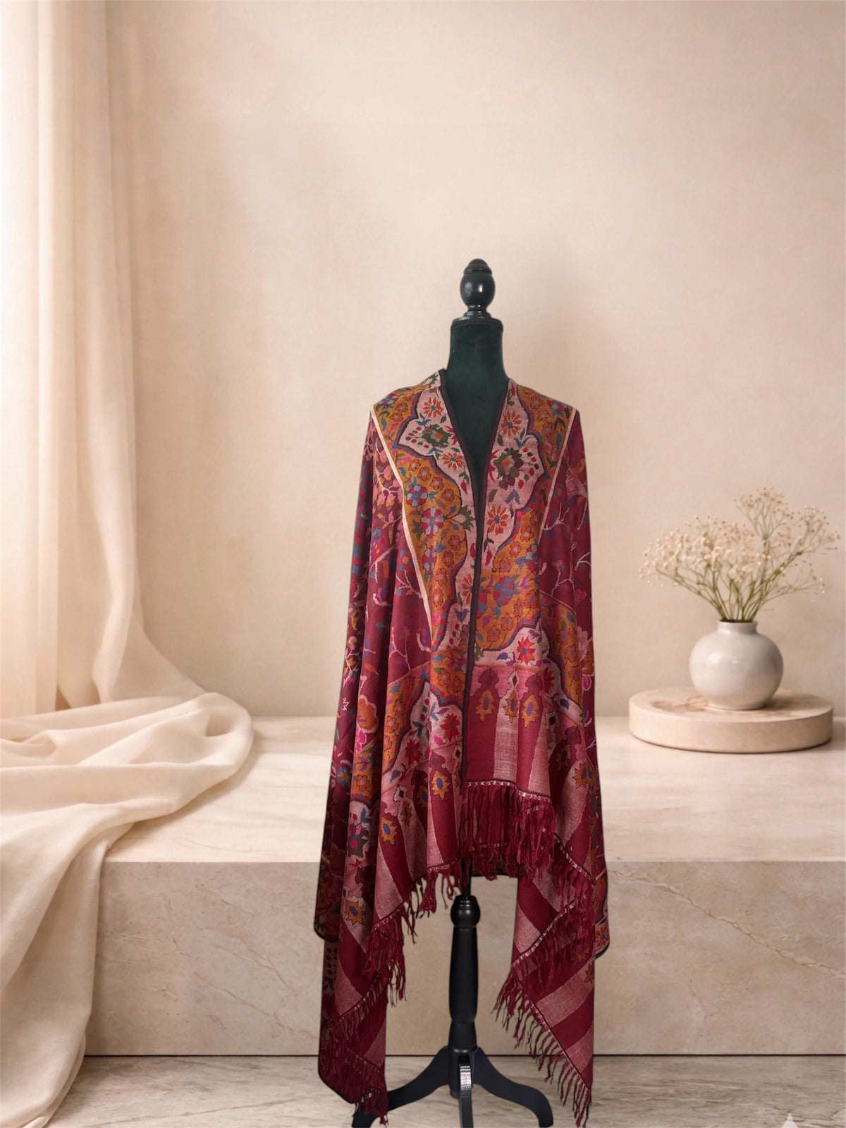Wine red Kani pashmina shawl with fringed striped ends worn over the shoulders, front view
