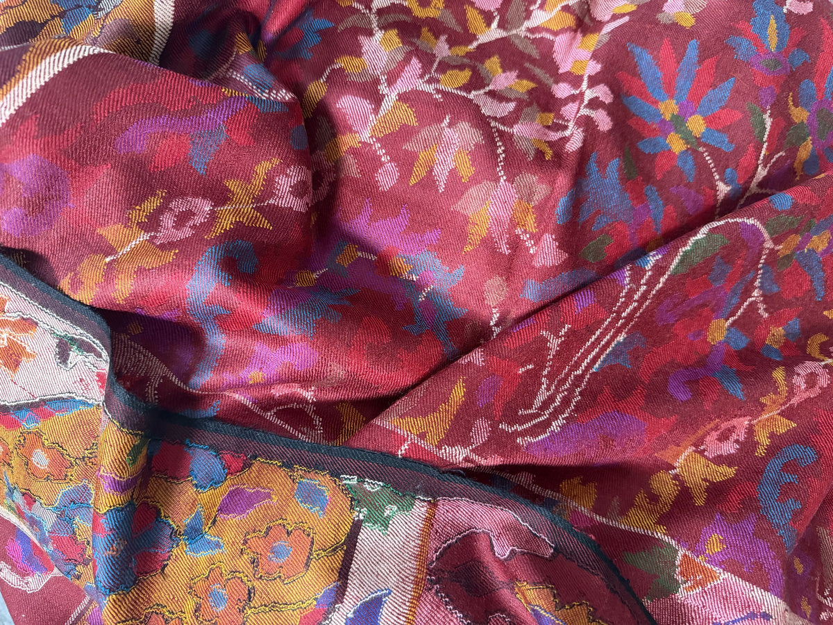 Close-up of Kani floral weave and ochre border on wine red pashmina